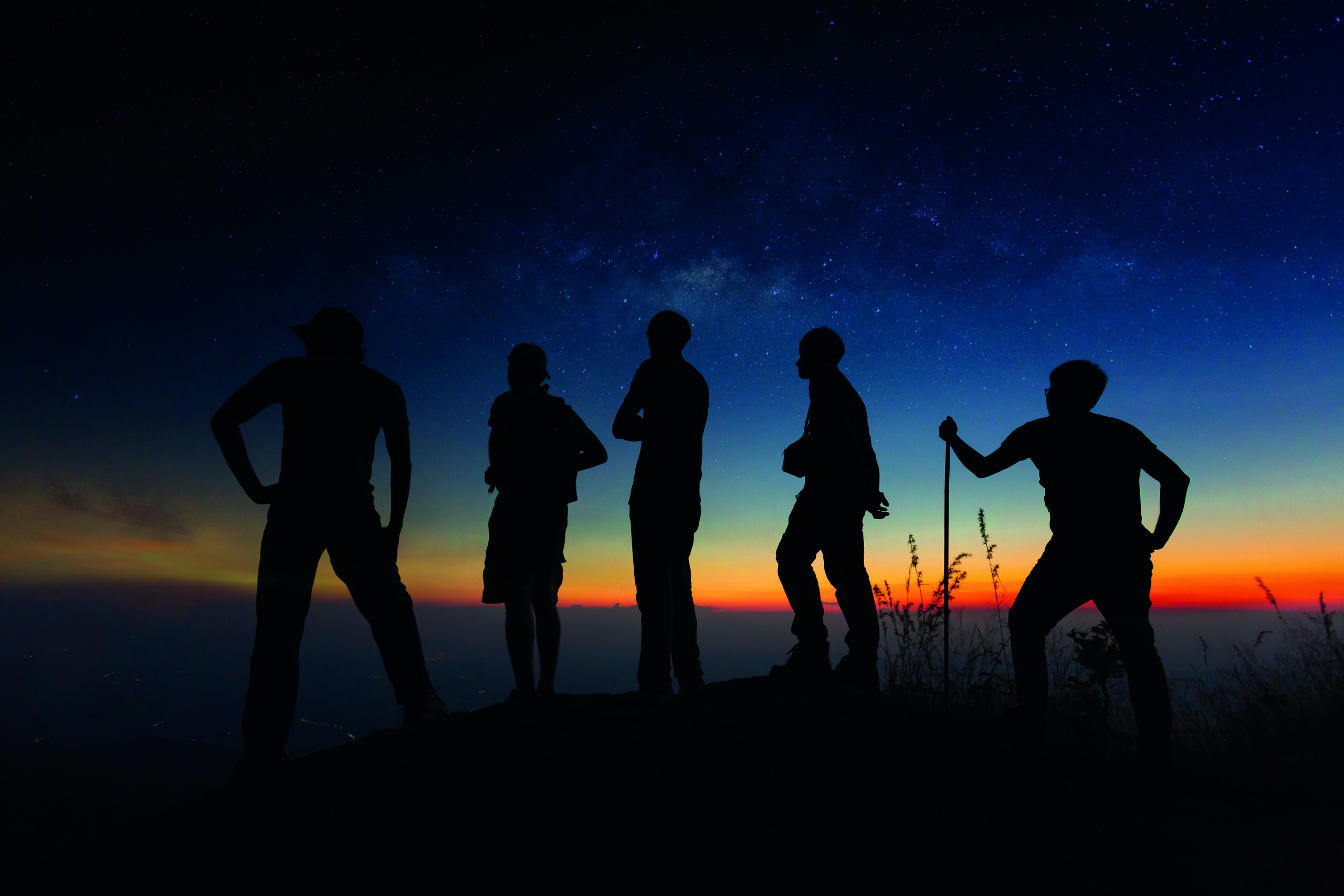 Silhouettes of people gathering together in nature looking on sk